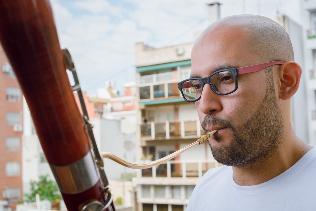 concentrated young latino venezuelan saxophonist man playing the bassoon outdoors.